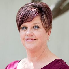 A photo of Jenny wearing a purple shirt and smiling at the camera.