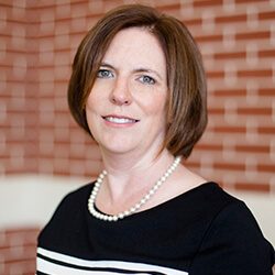 A photo of LaDonna standing outside in front of a brick wall smiling at the camera.