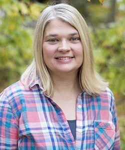 A photo of Tammy standing outside in front of a tree smiling at the camera.