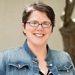 A photo of Dawn standing outside in front of a tree smiling at the camera.