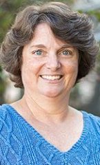 A photo of Christine standing outside in front of a tree smiling at the camera.