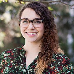 A photo of Stephanie standing outside in front of a tree smiling at the camera.