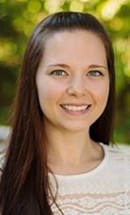 A photo of Kari standing outside in front of a tree smiling at the camera.