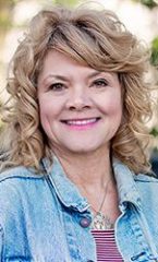 A photo of Cyndi standing outside in front of a tree smiling at the camera.