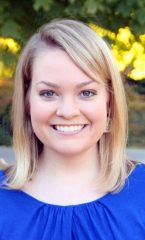 A photo of Bethany standing outside on a sunny day smiling at the camera.