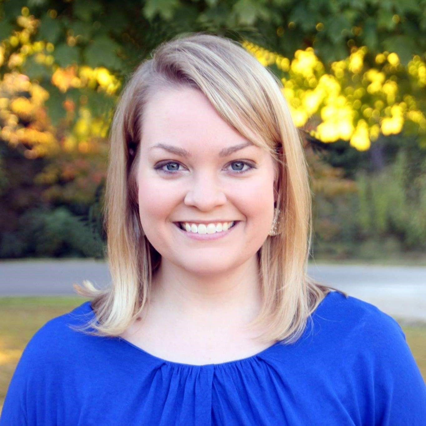 A photo of Bethany standing outside on a sunny day smiling at the camera.