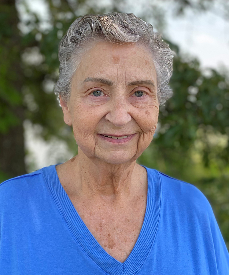 Woman with short gray hair wearing a light blue shirt