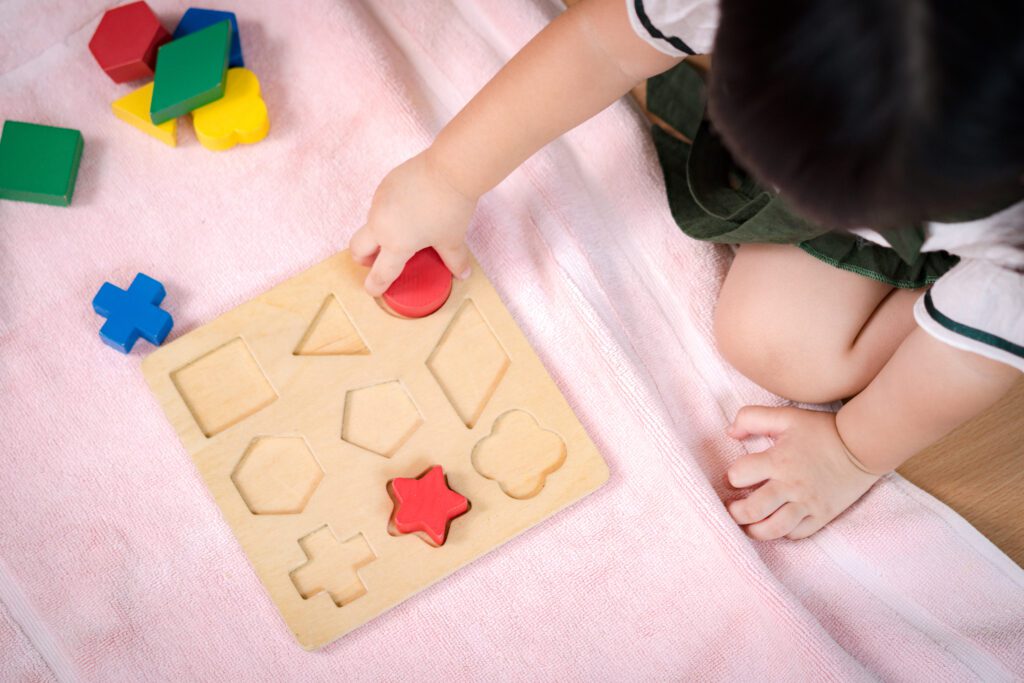 Toddler playing with a wooden shape puzzle.