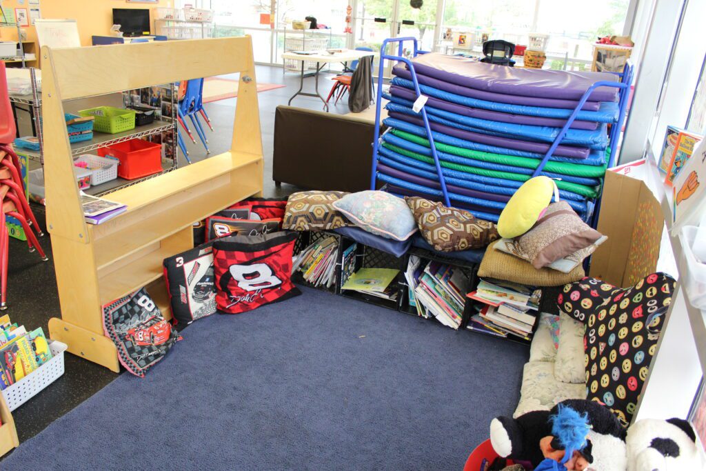 Library center with carpet, soft pillows and books stored in containers.