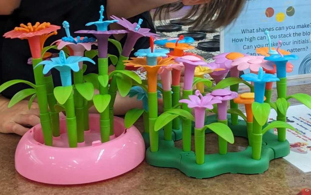 A child's fine motor activity in progress. They are building a desk decoration using interlocking flower and stem elements.