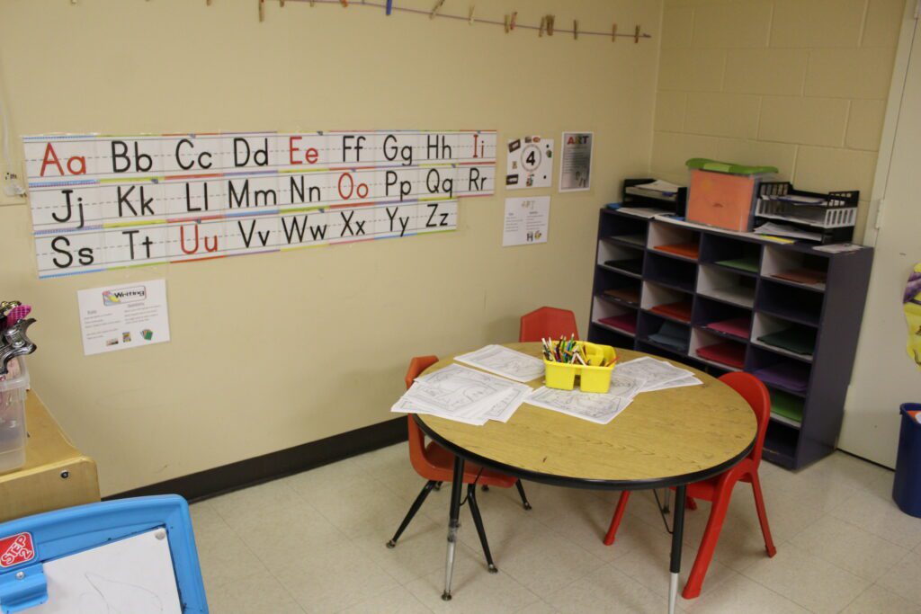Writing area with a table, chairs, storage, and writing materials.